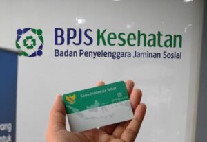 BPJS Kesehatan card held in hand with BPJS Kesehatan logo and text 'Badan Penyelenggara Jaminan Sosial' in the background, highlighting BPJS benefits for foreign workers in Indonesia.