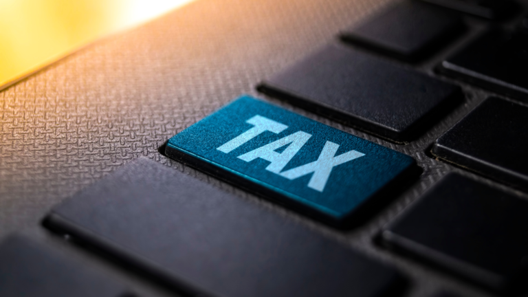 A close-up of a keyboard with a blue "TAX" key, representing the challenges of the Coretax System technical issues in Indonesia.