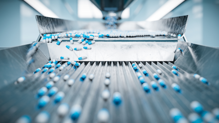 A close-up of blue and white capsules on a pharmaceutical production line, highlighting Indonesia’s Pharmaceutical Industry.