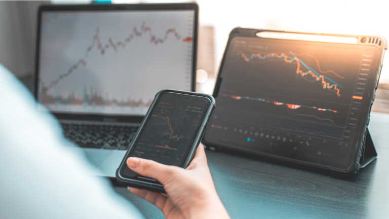 A user monitoring stock market trends on a smartphone, tablet, and laptop, illustrating the rise of the Bukalapak Digital Investment Platform.