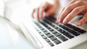 Hands typing on a laptop keyboard illustrating OSS Indonesia registration process.