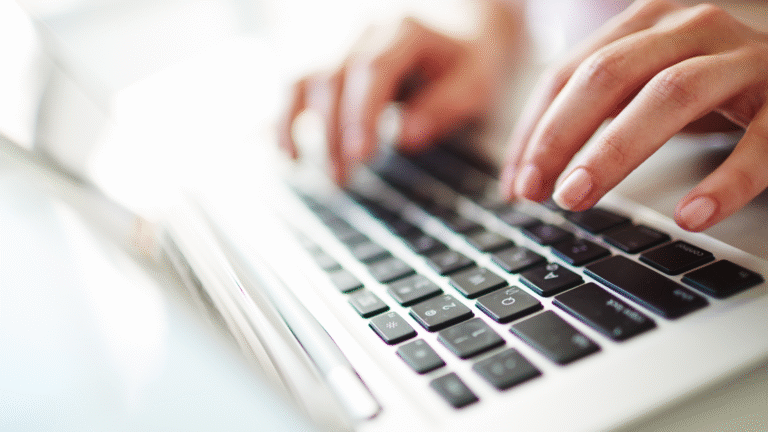 Hands typing on a laptop keyboard illustrating OSS Indonesia registration process.