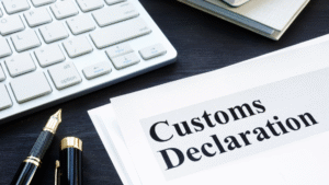 A printed customs declaration document placed on a dark desk beside a fountain pen, a white computer keyboard, and notebooks, representing the preparation process for submitting an Indonesia Customs Declaration.