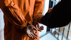 Illustration of an officer handcuffing a detainee in prison uniform during an Investor KITAS abuse arrest in Indonesia.
