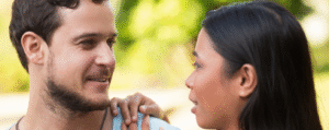 Interracial couple smiling and talking in a park, symbolizing international marriage and the importance of a spouse visa.