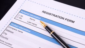 A fountain pen rests on a "REGISTRATION FORM" with "Personal information" and "Contact information" sections, symbolizing the process to register a local business in Jakarta.