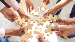 A group of office workers holding wooden puzzle blocks symbolizing how to restructure a PT in Indonesia.
