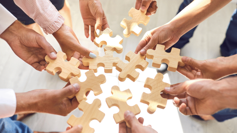 A group of office workers holding wooden puzzle blocks symbolizing how to restructure a PT in Indonesia.