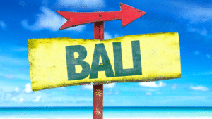 A colorful directional sign towards Bali on a tropical beach, symbolizing travel shifts influenced by the Thailand-Cambodia conflict.