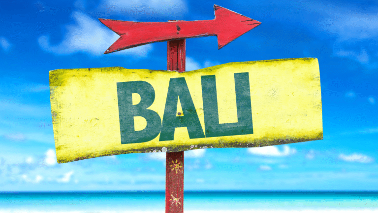 A colorful directional sign towards Bali on a tropical beach, symbolizing travel shifts influenced by the Thailand-Cambodia conflict.