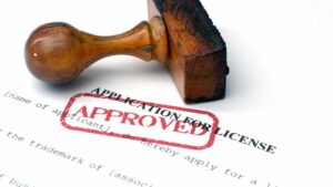 A rubber stamp marked “Approved” on a business license application form, symbolizing successful licensing.