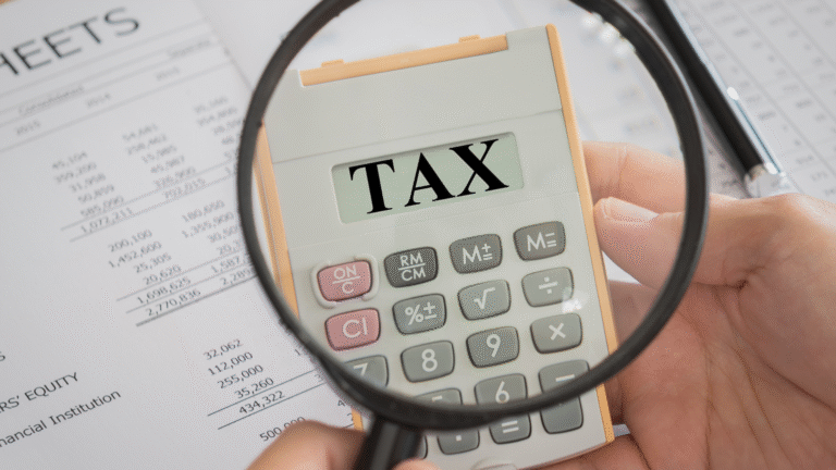 Close-up of a calculator displaying the word TAX under a magnifying glass, symbolizing taxation in Indonesia and financial compliance.