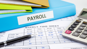Payroll outsourcing in Indonesia concept with payroll binder, timesheet, calculator, and pen on desk.