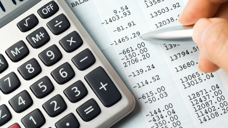 A person's hand holds a pen, pointing to a negative number on a financial spreadsheet, with a calculator next to it, calculating EBITDA