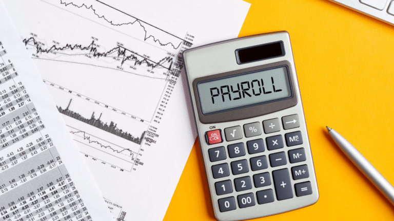 Calculator displaying the word payroll alongside financial charts and documents, representing payroll calculation in Indonesia.