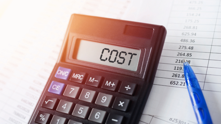 Calculator displaying the word “COST” on screen beside financial documents, symbolizing PT PMA cost in Indonesia.