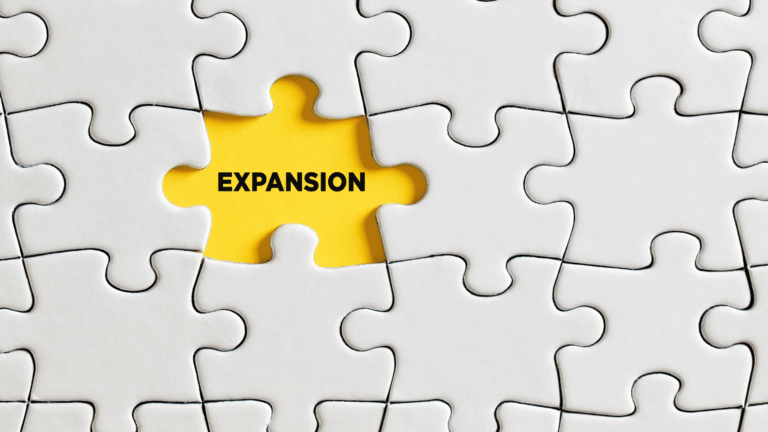 A white puzzle with a yellow piece labeled ‘EXPANSION,’ symbolizing PT PMA expansion in Indonesia as the missing piece completing a company’s business growth.