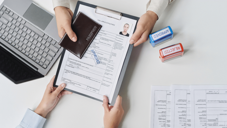 Hands holding a passport and an approved visa application form beside a laptop, symbolizing a successful Bali immigration visa extension process.