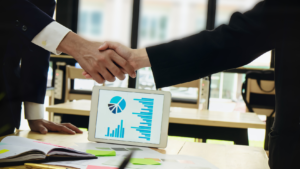 Two businessmen shaking hands symbolizing a joint venture agreement between two companies.