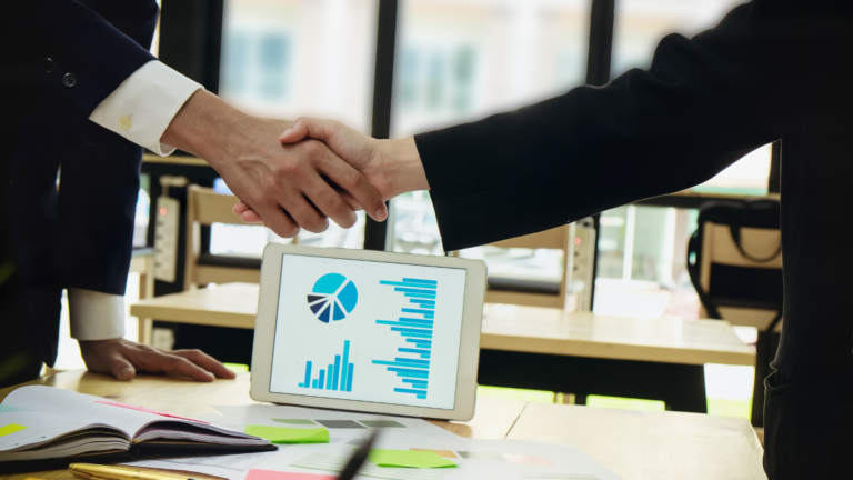 Two businessmen shaking hands symbolizing a joint venture agreement between two companies.