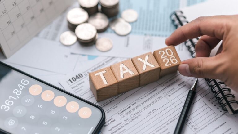 Wooden blocks spelling TAX 2026 on top of financial documents, coins, calculator, and calendar symbolizing Indonesia Tax Planning for foreign businesses.