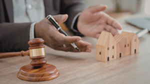 Legal consultation scene illustrating ppjb vs ajb in Indonesian property law, showing a gavel, documents, and house models during a property transaction discussion.