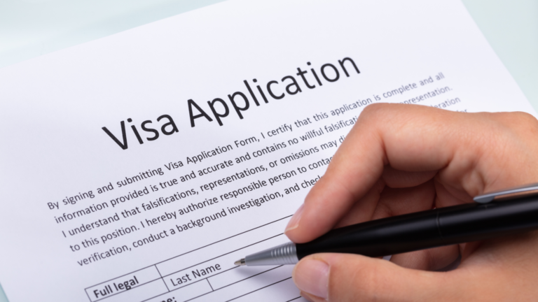 Hand filling out a visa application form, illustrating restrictions on running a business on a tourist visa in Indonesia.
